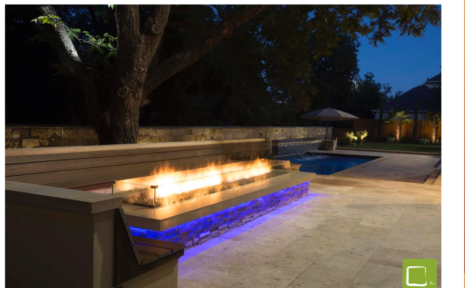 Modern Cantera Pool linear fire feature and water wall at dusk - luxury landscape design by Original Landscape Concepts in Preston Hollow, Dallas